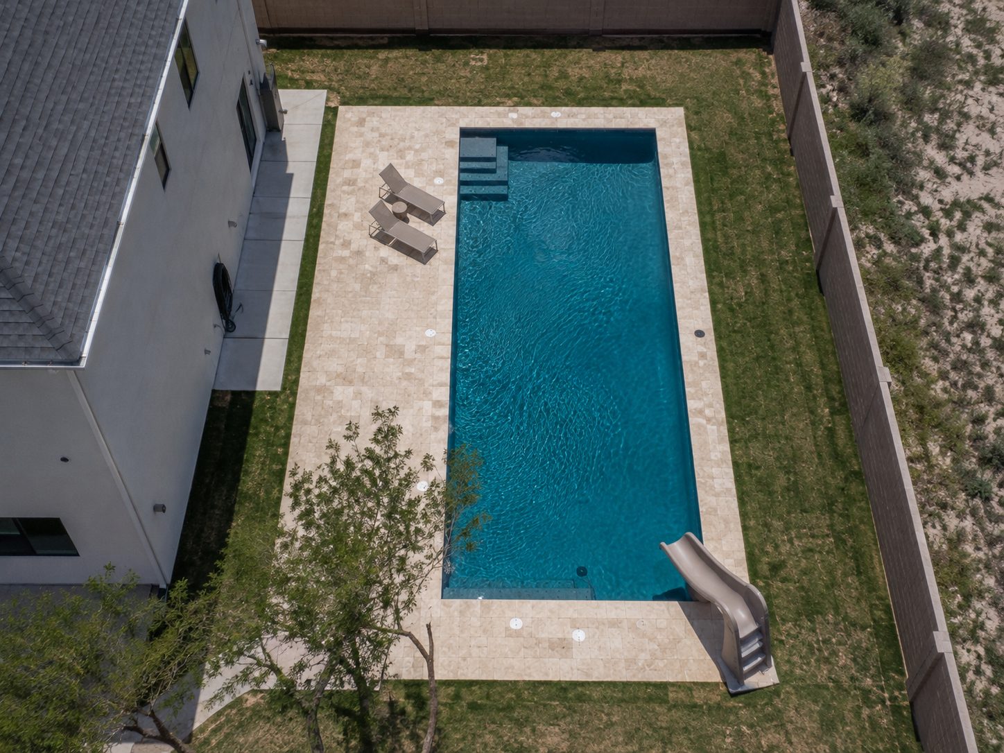 Aerial view of pool with slide and tanning ledge