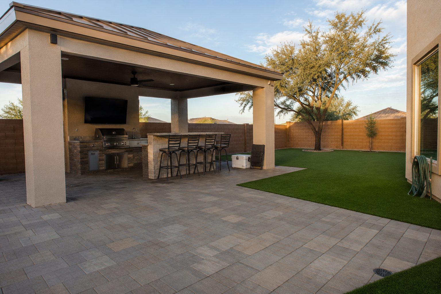 Paver patio with covered outdoor kitchen and turf lawn